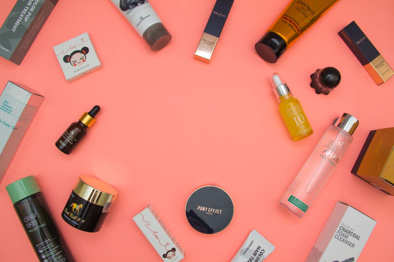 Top view of various cosmetic products for skincare and beauty in different bottles placed on pink surface