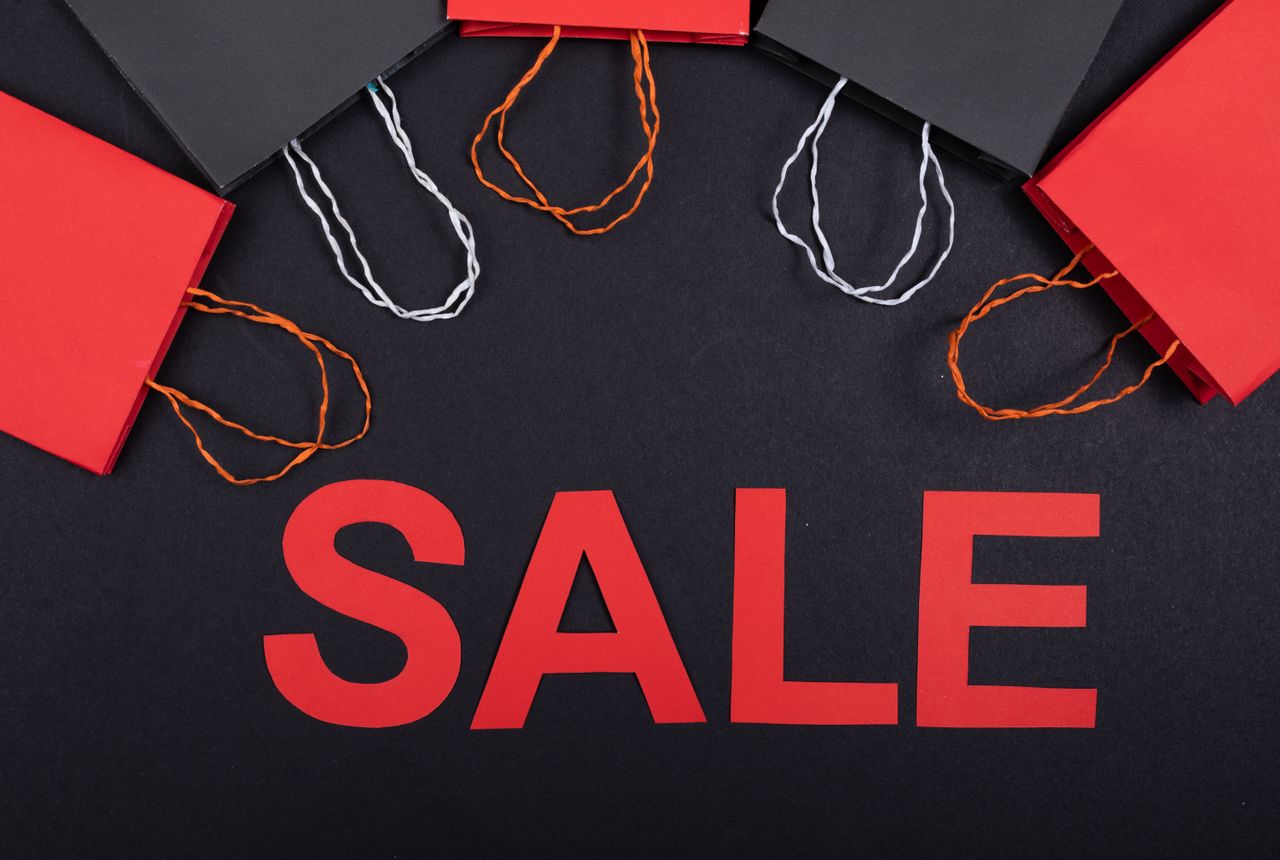 Top view of red and black shopping bags with sale text on a black background.